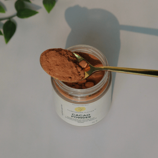 Cacao powder in a spoon above its jar